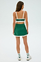 In a plain background, a person stands with their back to the camera, wearing a green athletic skirt, striped socks, and sneakers. They sport a SPLITS59 Monah Rigor Bra in Arugula/White, ready for gym workouts.
