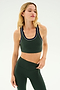 A person with long blonde hair wears a dark green Robbie Airweight Bra - Military/Indigo by SPLITS59, paired with matching leggings, standing against a white background, ready for hot yoga.