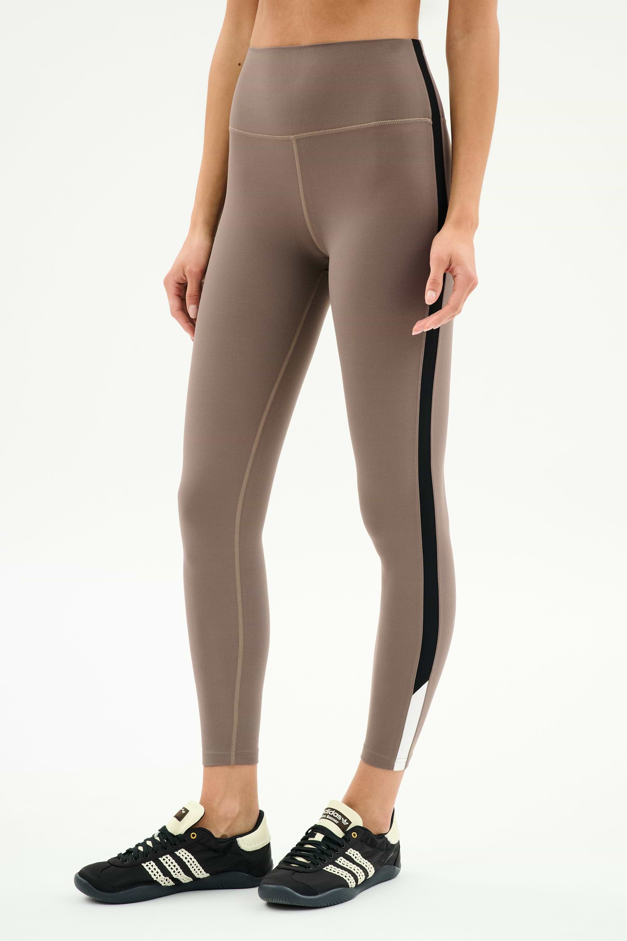 Model wears SPLITS59 Layla Airweight High Waist 7/8 leggings in Lentil/Black, showcasing ultra-soft fabric and black side stripe with black athletic shoes—ideal for hot yoga or daily wear, set against a plain white background.