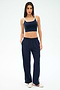 A woman faces forward wearing SPLITS59's Maxie Rigor Track Pant in Indigo/White with white trim, a coordinating navy crop top, and white sneakers.