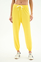A person wears SPLITS59's Andie Oversized Fleece Sweatpant in bright yellow, featuring a white drawstring, paired with white sneakers and standing against a plain white background.