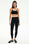 A woman stands against a plain white background wearing the SPLITS59 Elliah Airweight Double Layer Bra in Black/White, paired with matching high-waisted leggings and black athletic shoes.