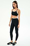 A woman stands against a white background wearing the SPLITS59 Elliah Airweight Double Layer Bra in Black/White.