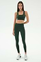 A woman faces forward against a white background, wearing the SPLITS59 Lexi Rigor Bra in Military/Blush with matching high-waisted leggings featuring side stripes and white sneakers.