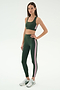 A woman wears the SPLITS59 Lexi Rigor Bra in Military/Blush—dark green with blush side stripes—paired with matching leggings and silver athletic shoes, standing against a plain white background.
