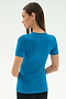 A woman with straight brown hair stands with her back to the camera, wearing the SPLITS59 Louise Rib Short Sleeve in Stone Blue against a plain light background.