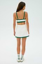 Facing away, a woman wears the SPLITS59 Monah Rigor Bra in white with green trim as part of a matching crop top and skirt set, paired with white socks and sneakers.