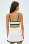 A woman wearing the SPLITS59 Monah Rigor Bra in White/Arugula stands with her back turned against a plain backdrop.