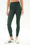 A person wears SPLITS59 Amber Airweight High Waist 7/8 leggings in Military/Spearmint, featuring a comfy nylon-spandex blend and green side stripe, paired with white sneakers with green stripes, standing against a white background.