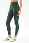 A person wears SPLITS59's Amber Airweight High Waist 7/8 leggings in Military/Spearmint, featuring a dark green hue with a light green stripe, paired with white sneakers with green stripes, against a plain light background.