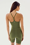 A woman is standing with her back to the camera, wearing the Airweight 6” Short Jumpsuit - Olive from SPLITS59, a fitted athletic one-piece outfit made from Airweight fabric with a racerback design.
