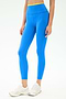 A person stands against a plain light background wearing SPLITS59 Dual High Waist Airweight 7/8 leggings in Classic Blue/Ray and white athletic shoes—an ideal outfit for hot yoga.