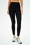 A person wearing SPLITS59's Easton Rigor High Waist 7/8 in Black/Chartreuse and white running shoes, ideal for high-impact workouts, stands against a plain background.