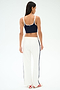 A woman faces away, wearing a navy crop top with white trim, SPLITS59 Maxie Rigor Track Pant in white/indigo featuring navy side stripes, and white sneakers with red stripes.