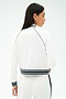 A woman is shown from the back wearing the SPLITS59 Hayes Varsity Rigor Jacket in white, featuring black trim and striped cuffs, paired with matching pants.