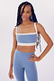 A young woman in a SPLITS59 Monah Rigor Bra - Steel Blue/White and leggings posing confidently against a plain white background.