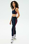 A person wears the SPLITS59 Ella Airweight Bra in Indigo/Pirate Red, paired with matching leggings, white socks, and silver sneakers, standing against a plain light background.
