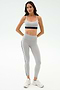 A woman stands against a white background wearing the SPLITS59 Emerson Airweight High Waist leggings in Dove Grey/Indigo and a light gray sports bra, perfect for hot yoga or Pilates, paired with white athletic shoes.