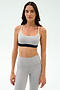 Woman wearing the SPLITS59 Emerson Airweight Bra in Dove Grey/Indigo with thin straps and high-waisted leggings, ideal for hot yoga or Pilates, stands against a plain white background.