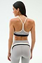 A woman stands with her back to the camera, wearing the SPLITS59 Emerson Airweight Bra in Dove Grey/Indigo and matching high-waisted leggings, perfect for hot yoga or Pilates.