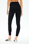 A person wears the SPLITS59 Mia Rigor Legging w/ Stripe in Black/White with white athletic shoes, photographed from the back against a plain background.