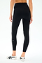A person wears the SPLITS59 Mia Rigor Legging w/ Stripe in Black/White with white athletic shoes, photographed from the back against a plain background.