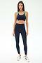 A woman faces forward, wearing the SPLITS59 Robbie Airweight Bra in Indigo/Spearmint with matching leggings and white sneakers, set against a plain white background.
