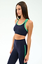A woman wears the SPLITS59 Robbie Airweight Bra in Indigo/Spearmint, paired with matching high-waisted leggings, standing against a plain light background.