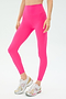 Wearing SPLITS59 Sprint High Waist Rigor 7/8 leggings in Berry and white athletic sneakers, a person stands against a plain light background.