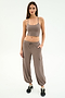A woman faces forward wearing the SPLITS59 Airweight Crop in Lentil with matching taupe cargo pants and black sneakers against a white background—ideal for hot yoga or casual outings.