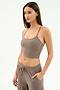 A woman wears the SPLITS59 Airweight Crop in Lentil with matching drawstring pants, one hand in her pocket against a plain backdrop—ideal for hot yoga or relaxing days.