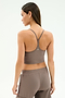 A woman with long brown hair stands against a plain light background wearing the SPLITS59 Airweight Crop in Lentil, paired with matching pants—perfect for hot yoga or any workout.
