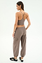 A woman faces away, wearing the SPLITS59 Airweight Crop in Lentil and matching joggers with black Adidas sneakers against a plain light background.