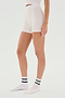 Person standing in white seamless fitted SPLITS59 Theo Rib Short - White and white socks with black and white logo. Cropped at chest level, side view against a plain white background, showcasing the tailored comfort of the SPLITS59 Theo Rib Short - White's classic design.