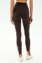 Model wears SPLITS59 River High Waist Airweight Stirrup in Dark Chocolate, styled as stirrup tights with white sneakers, shown from the back against a plain background.