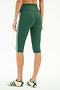 A person is shown from the back wearing SPLITS59 Ella High Waist Airweight Capri leggings in Arugula/White with white side stripes, paired with white sneakers featuring green stripes, combining sporty style and comfort.