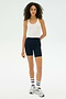 Against a plain white background, a person wears the SPLITS59 Ashby Rib Crop in white, navy cycling shorts with red stripes, white socks, and gray sneakers—ideal for gym workouts or casual outings.