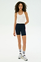 Against a plain white background, a person wears the SPLITS59 Ashby Rib Crop in white, navy cycling shorts with red stripes, white socks, and gray sneakers—ideal for gym workouts or casual outings.
