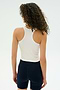 A person with curly hair, wearing the SPLITS59 Ashby Rib Crop in white and black shorts, stands with their back to the camera against a simple light background.