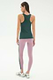 A woman faces away, ready for yoga or running in the SPLITS59 Kiki Rib Tank Full Length - Military, light purple leggings with a dark stripe, and white running shoes against a plain light background.