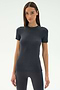 A woman with straight brown hair wears the SPLITS59 Louise Rib Short Sleeve in Graphite with black leggings, perfect for yoga or gym workouts, standing against a plain white background.