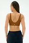 A person with braided hair is shown from the back wearing the SPLITS59 Airweight Scoop Back Bra in Honey and dark athletic pants against a plain background.