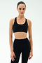 A woman faces forward in a black SPLITS59 Sara Airweight Bra and high-waisted leggings, ready for hot yoga or Pilates against a plain light background.