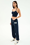 A woman wears the SPLITS59 Airweight Crop - Indigo with matching drawstring sweatpants featuring “59” on the left leg, plus white sneakers with navy stripes—ideal for hot yoga or casual outings.