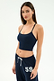 A woman stands against a plain background wearing the SPLITS59 Airweight Crop - Indigo and matching indigo sweatpants with "59" on the hip—ideal for hot yoga or relaxed, casual days.