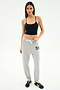 A woman stands against a white background wearing a black SPLITS59 Airweight Crop, light gray sweatpants with "59" on the left side, and black sneakers—ideal for hot yoga or relaxed casual days.