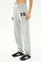 A person wearing SPLITS59 Andie Oversized Fleece Varsity 59 Sweatpant in Heather Grey/59, featuring "59" on the left thigh, white drawstring, and paired with black athletic shoes with white stripes.