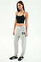 A woman stands against a white background wearing the SPLITS59 Airweight Crop in black, light gray sweatpants with "59" on the left leg, and black Adidas sneakers.