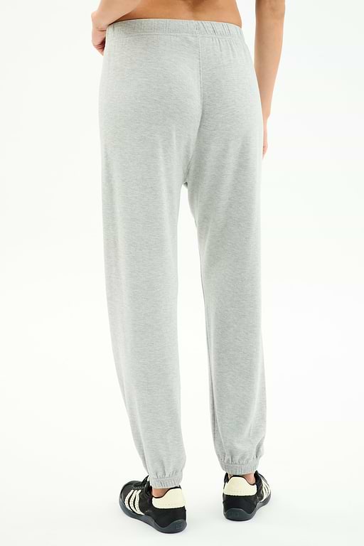 A person is shown from the back against a plain white background wearing SPLITS59’s Andie Oversized Fleece Varsity 59 Sweatpant in Heather Grey/59 paired with black-and-white sneakers.