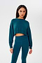 A woman wearing a SPLITS59 Noah Fleece Crop Sweatshirt in Peacock and leggings.